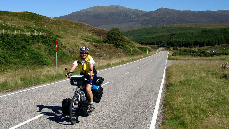 Radlerin auf Straße durch die Highlands.