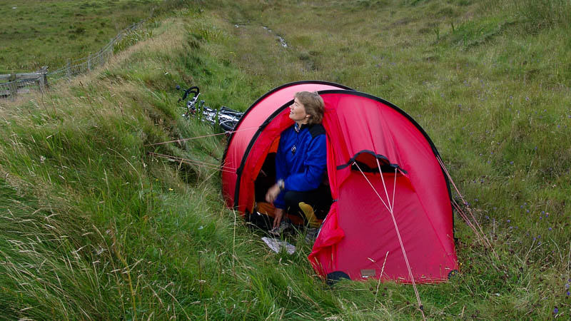 rotes Zelt steht über Bach im Grünen, Insel Barra Schottland