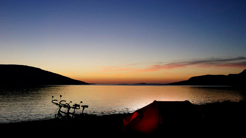 Sonnenuntergang mit Rad und Zelt an einem schottischen Loch