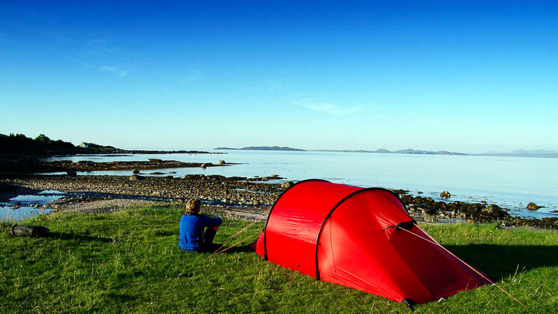 Rotes Zelt direkt am Wasser, Frau blickt aufs Wasser