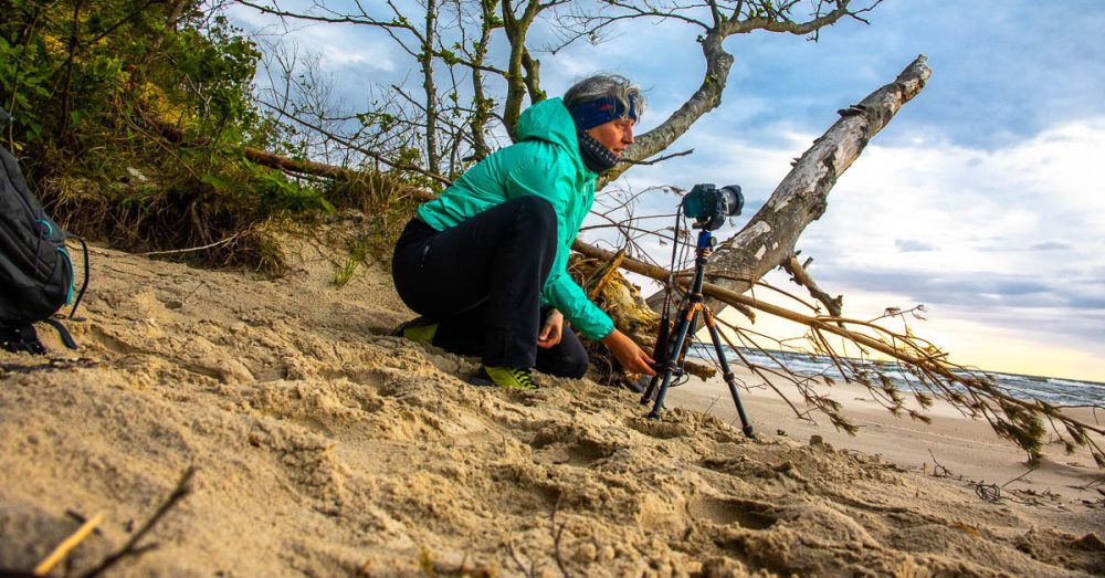 Beate Steger mit grüner Jacke und Buff Stirnband beim Fotografieren in Polen an der Ostseekueste