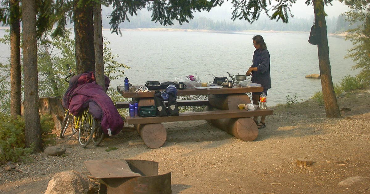 Beate Steger kocht auf dem Trangia Kocher das Abendessen direkt mit Blick auf den See